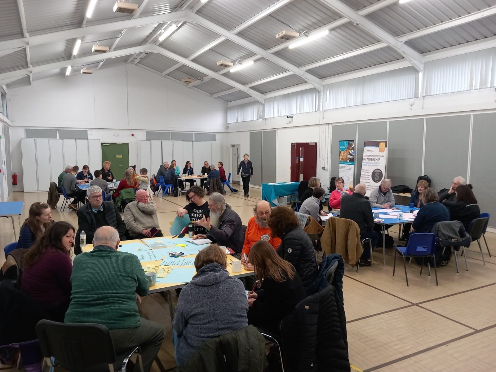 A group of people sitting around tables in a large room, having conversations