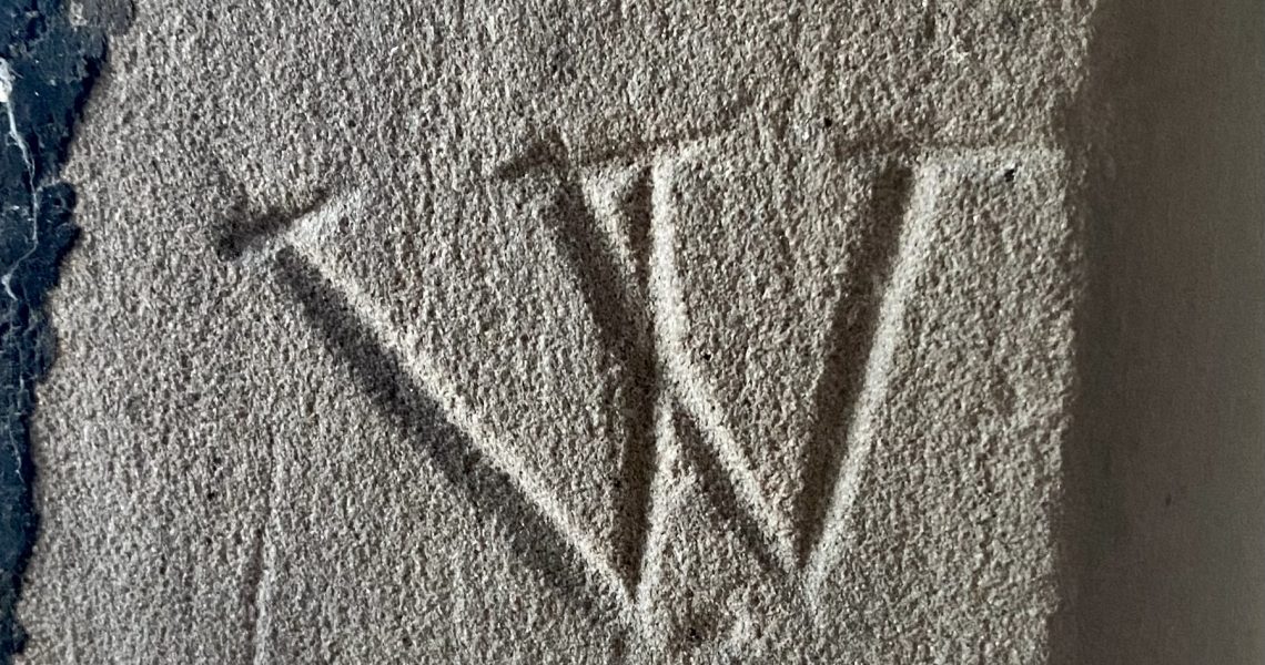a 'W' shaped mark carved into stonework inside a church